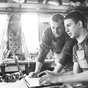 Mechanics looking at laptop in workshop 