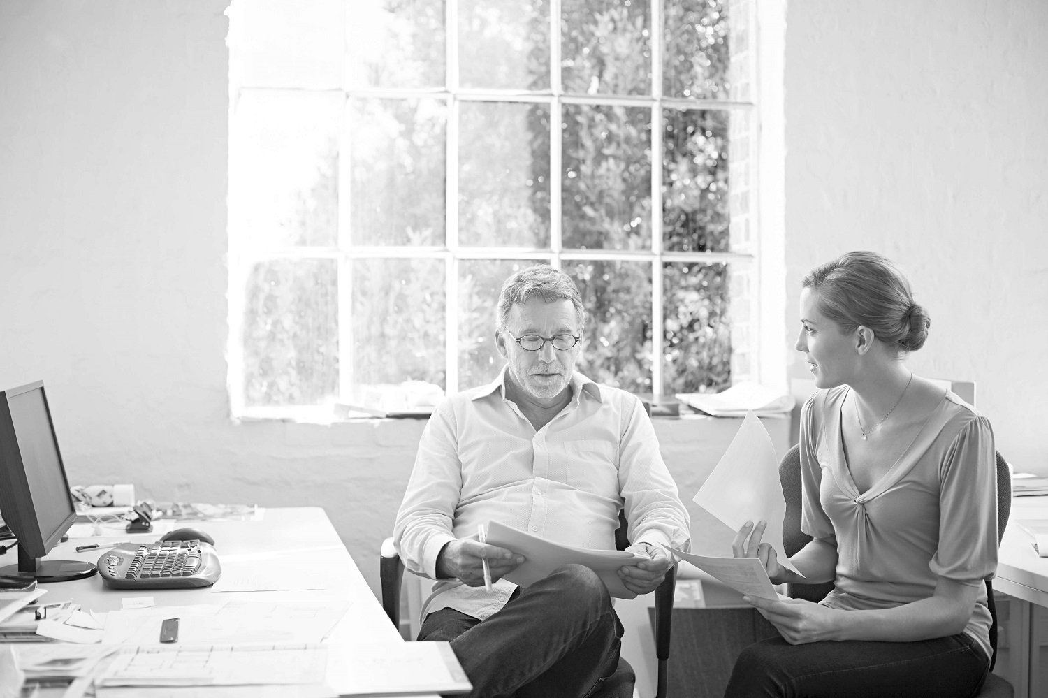 Two people sitting at desk reading papers