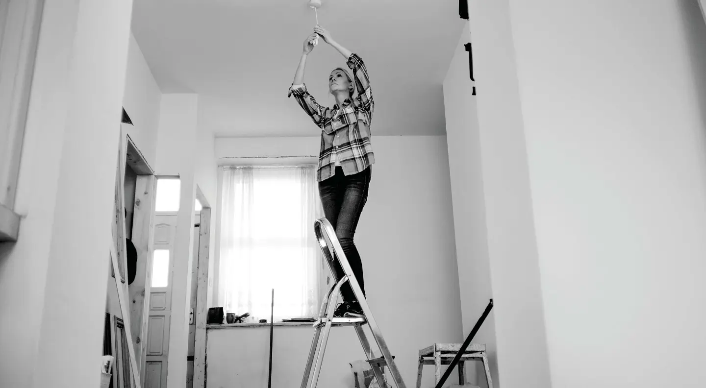 Person fixing lightbulb on ladder 